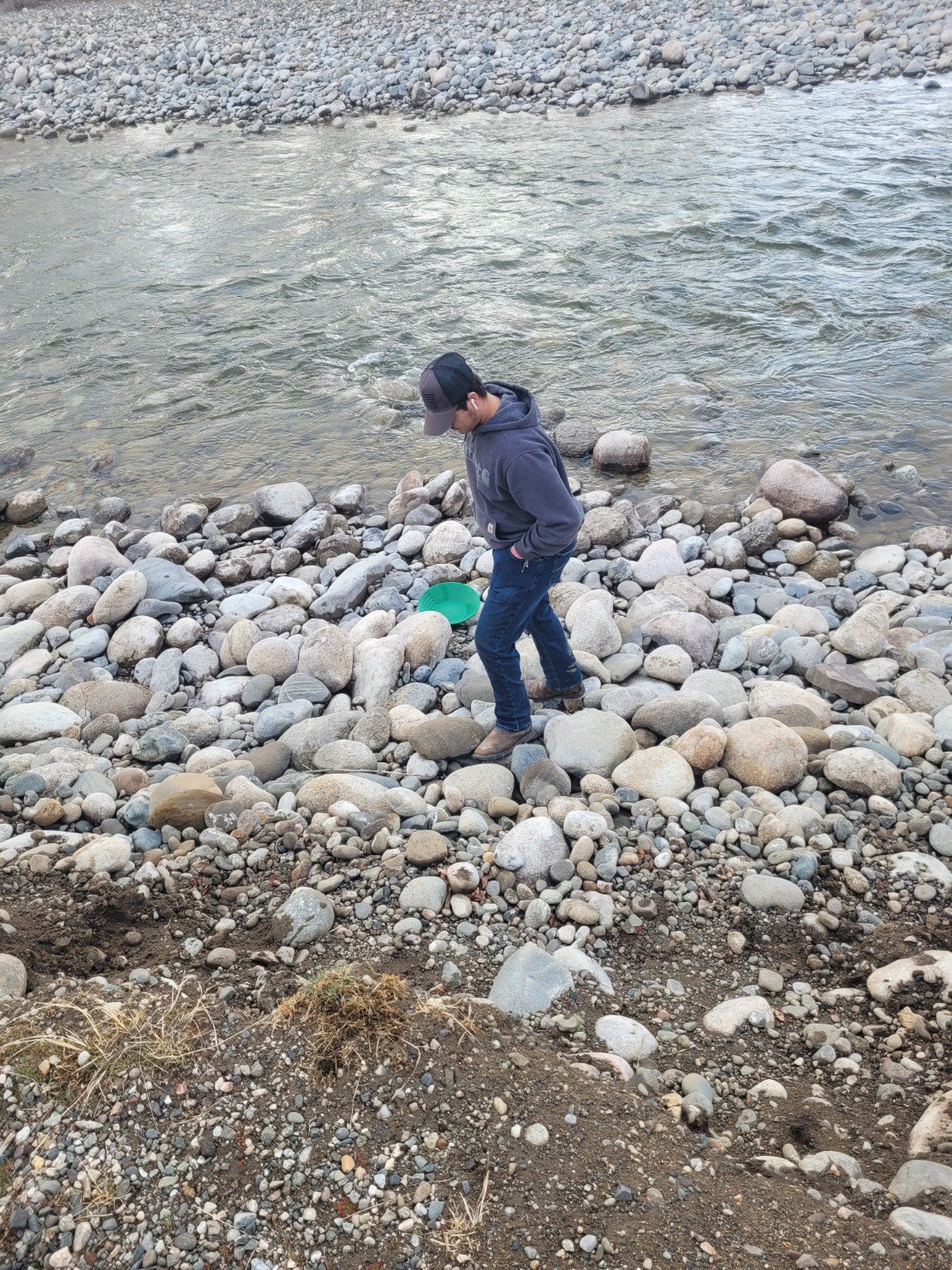 A young family member panning beside a river